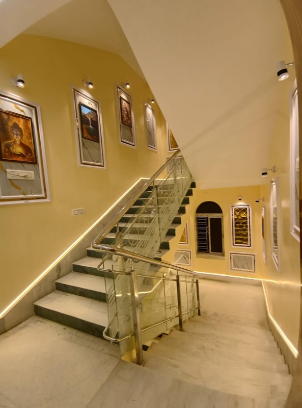 Bright staircase lobby with glass railing and wall art