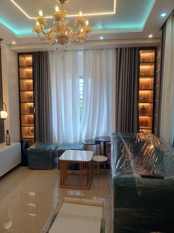 Living seating beside curtain wall with chandelier and display shelves